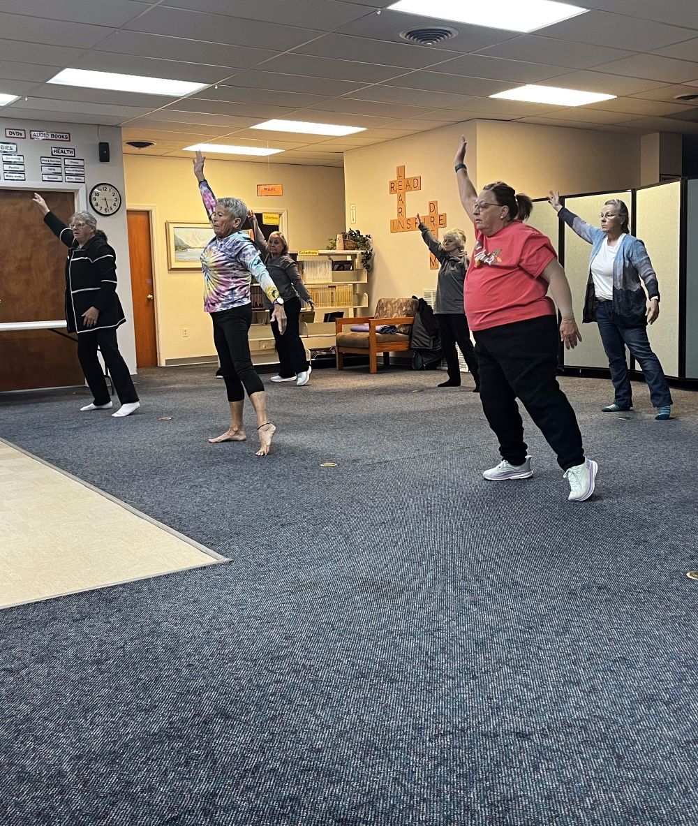 A group of older women dance on a carpeted floor.
